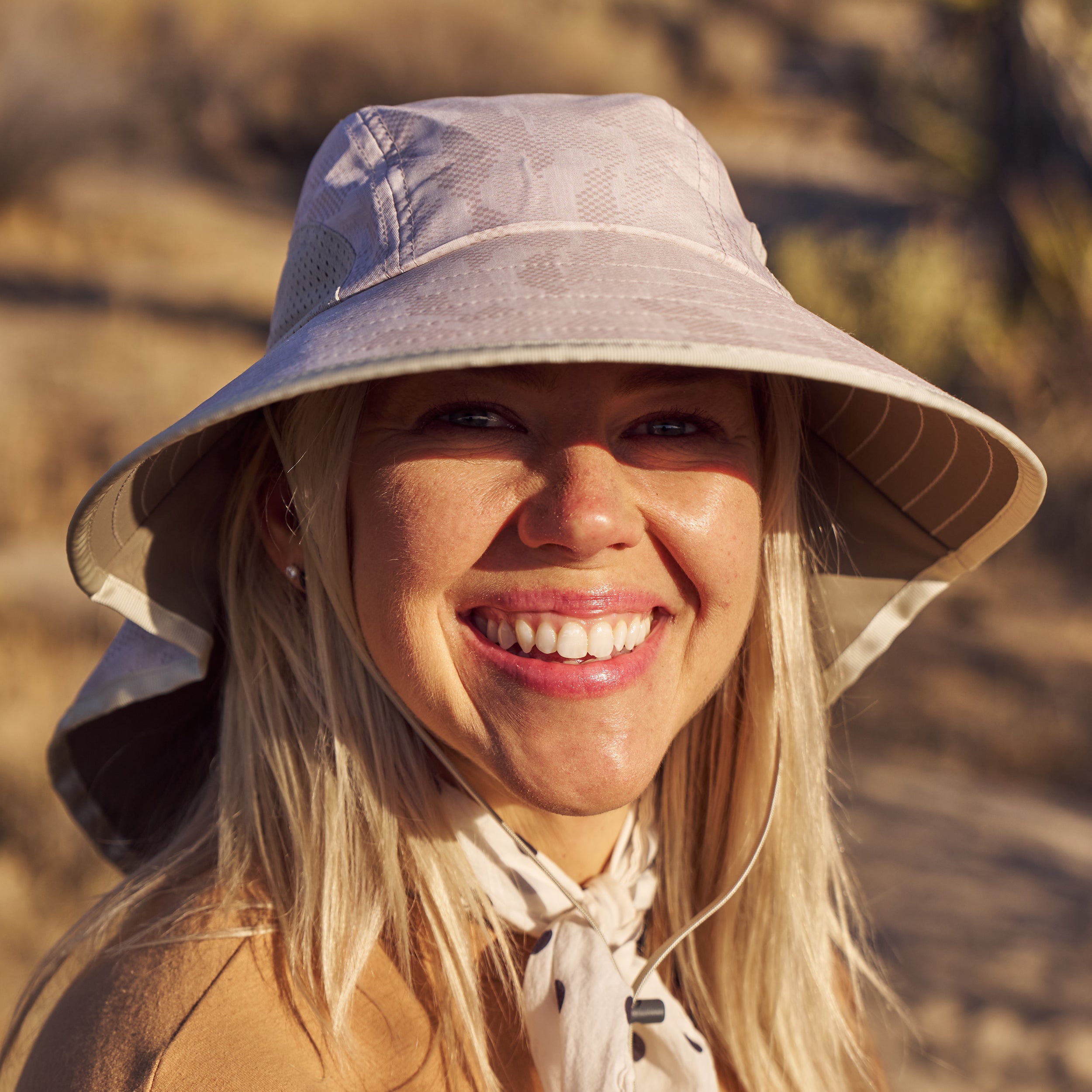 A woman in a desert setting wearing a Sunday Afternoons Adventure hat in the color Cream Terrain.